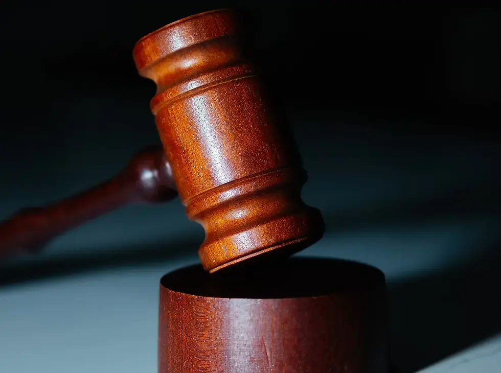 A wooden gavel poised above a striking block with a dark background, highlighting its polished texture and legal significance.