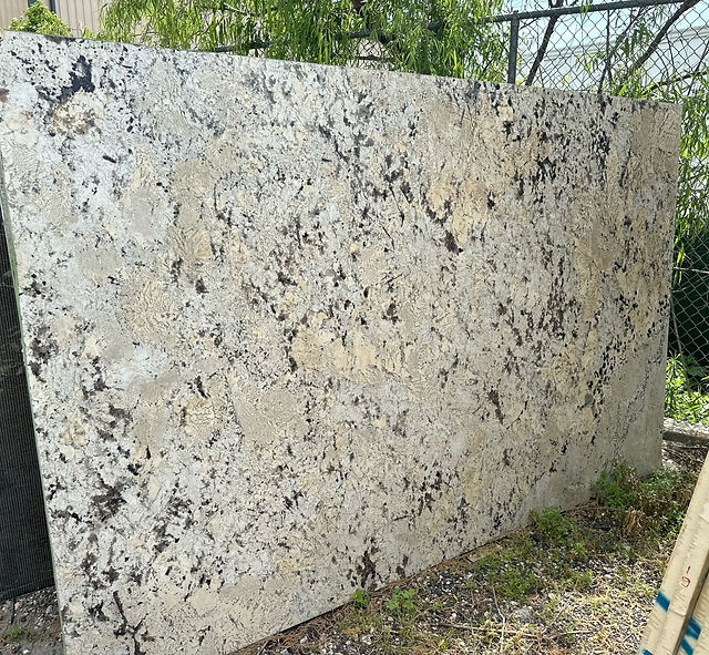 Large polished granite slab with dark speckles outdoors