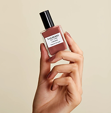 Woman's hand holding a neutral nail polish in square glass bottle
