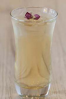 A glass of honey rosebud tea with a delicate flower floating on the surface, showcasing its vibrant colors and inviting aroma.