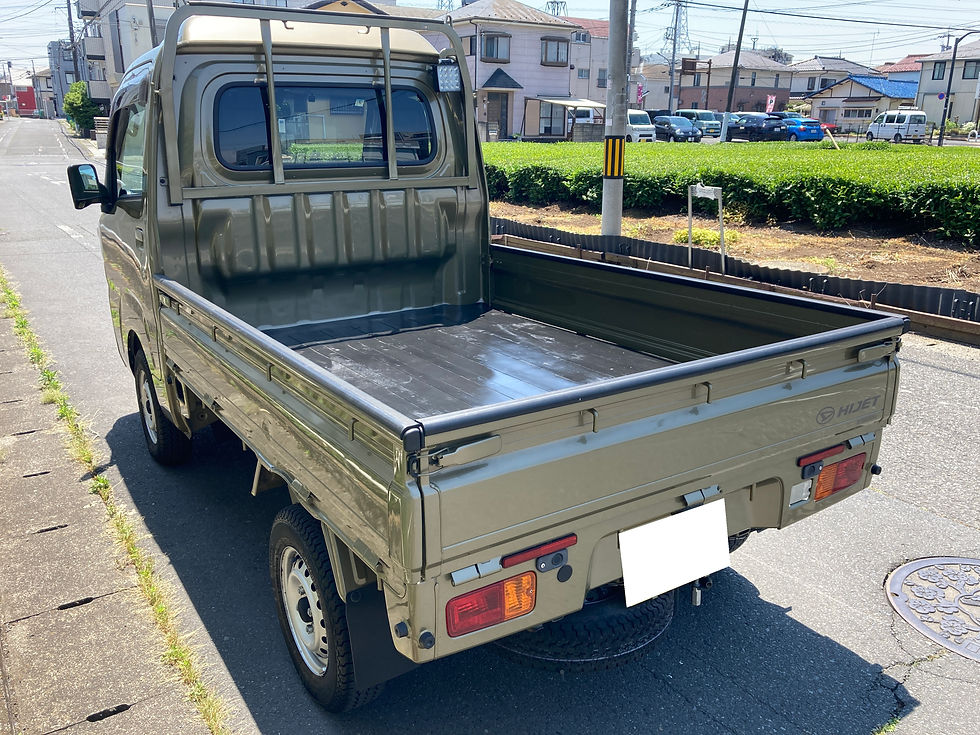 緑色のハイゼットトラックが住宅街の道路に停車。日差しが強く、周囲には住宅や駐車された車、緑の植栽が見える。