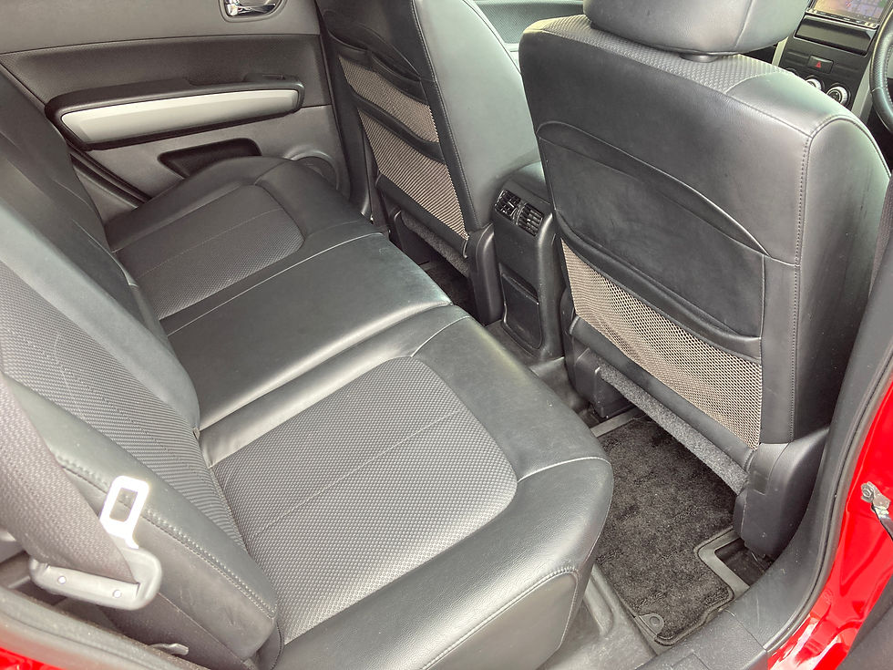 日産エクストレイルの黒いシートの後部座席。赤いドア枠が見え、空席の静かな車内が写っている。