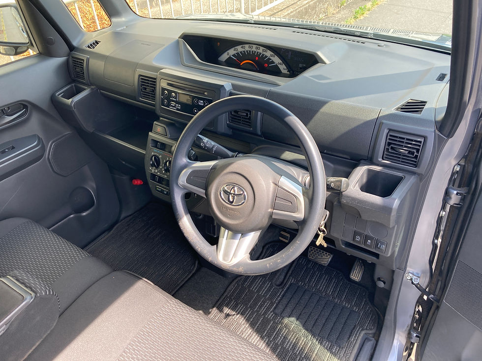 ピクシスメガの運転席まわり。黒い内装と丸いハンドル、ダッシュボード、メーターが見える、日差しの入った空の車内。