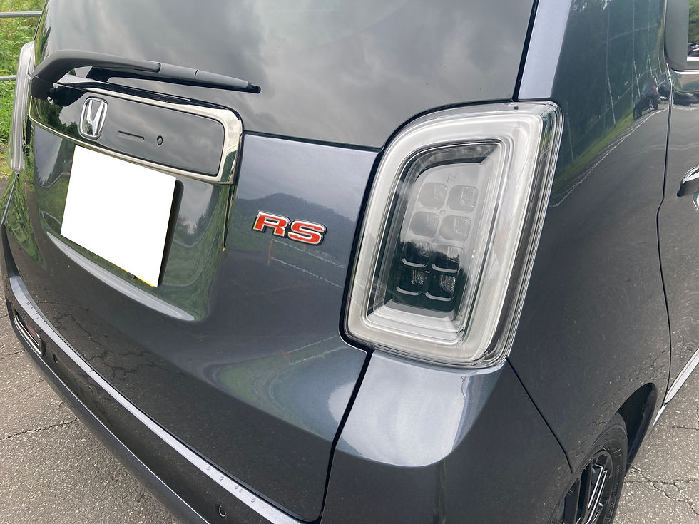 グレーのN-oneRSのリアを近接で撮影。RSエンブレム、右のLEDテールランプ、白く隠されたナンバープレートが見え、屋外の道路脇に停車している。