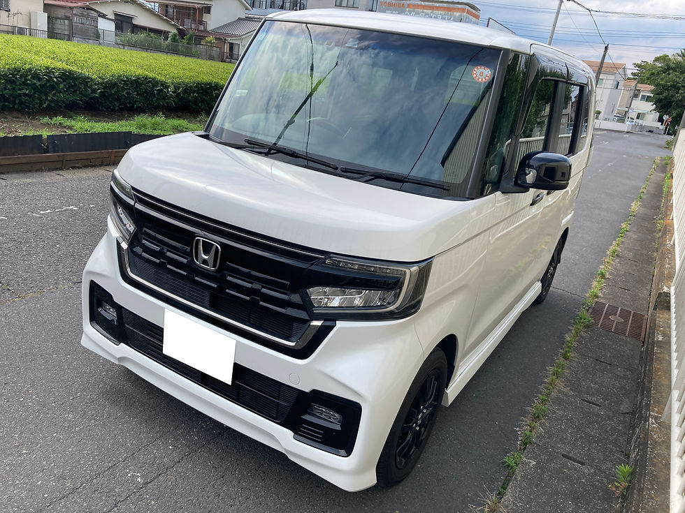 住宅街の路上に停まる白いホンダのN-BOX。黒いグリルと大きなフロントガラスが目立ち、静かな晴れ空の下にある。