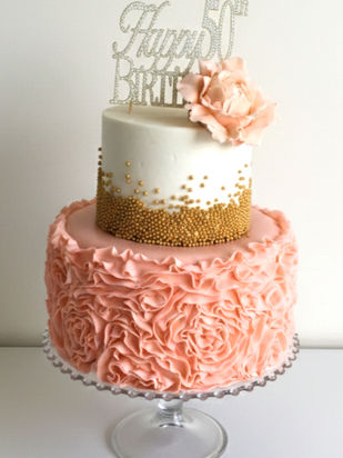 Pink and gold birthday cake with ruffled pink fondant and sugar flower.