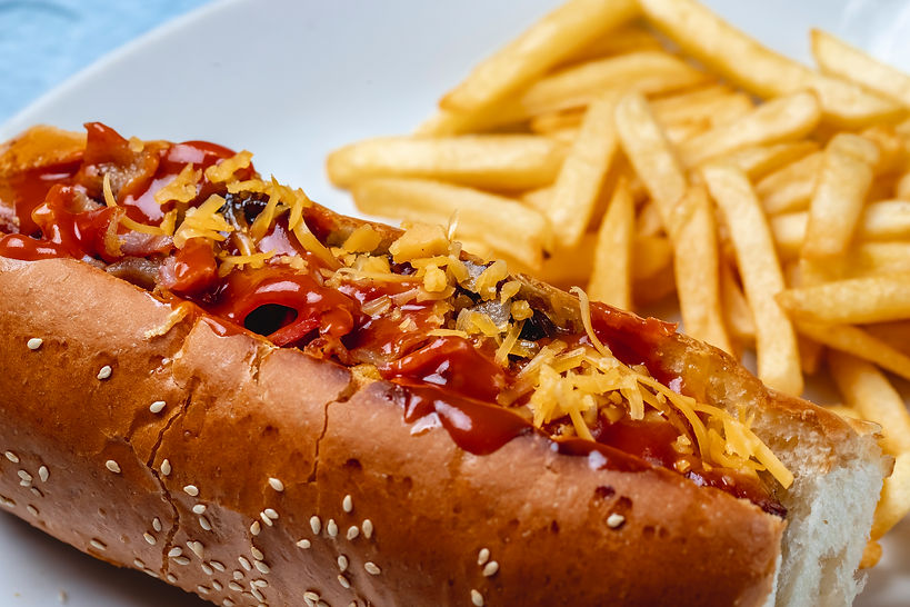 side-view-hot-dog-grilled-sausage-with-caramelized-onion-cheese-ketchup-french-fries-table