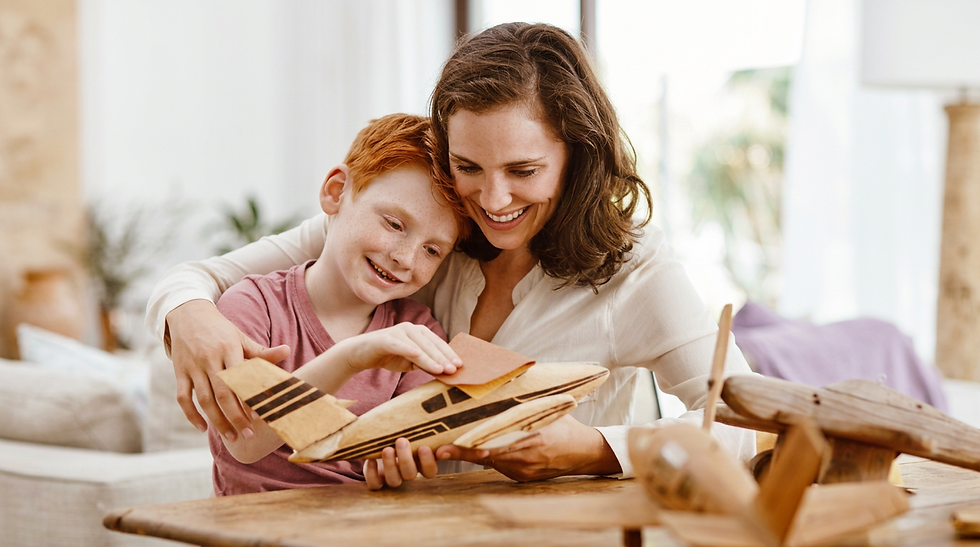 Studio photography of a mother and her son building a wooden toy airplane model, sharing a warm and joyful moment of connection. Soft, natural lighting creates an intimate and gentle atmosphere.