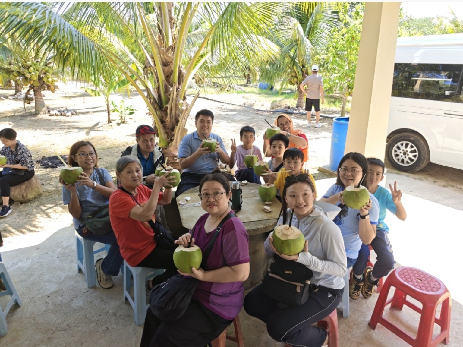 Families drinking fresh coconut during weekend visit at Potai Farmstay