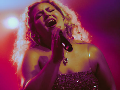 Molly Grace performing at Saint Andrew's Hall in Detroit MI, vocalist in a sequined strapless dress singing with eyes closed under deep pink and purple stage lighting