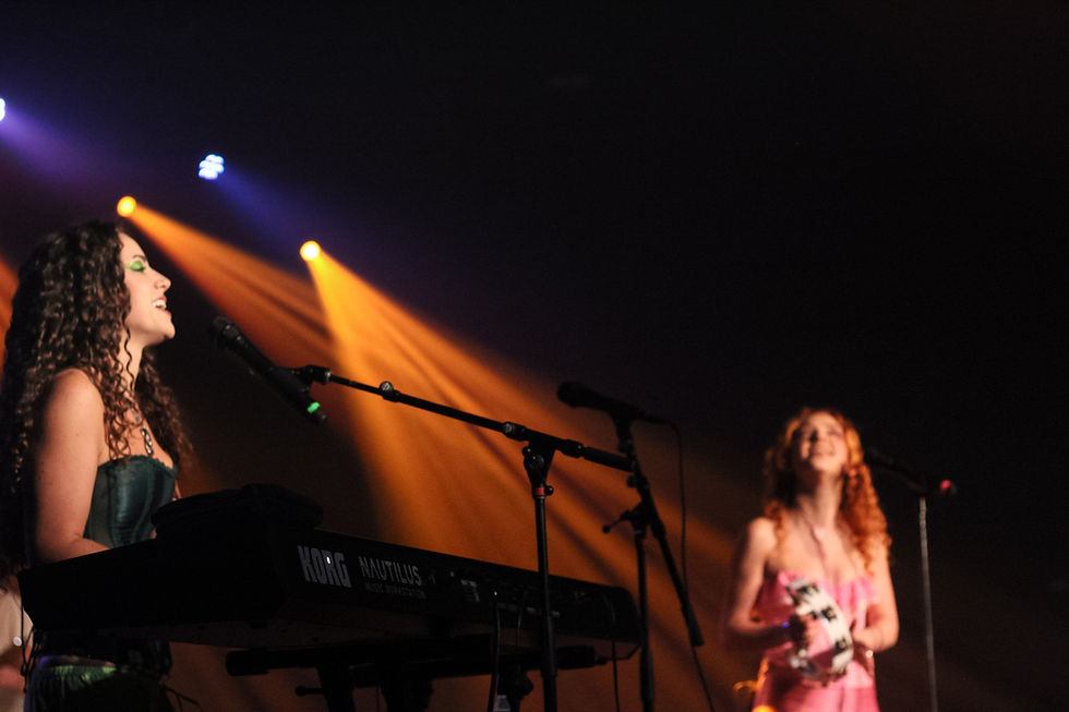 Two women on stage with keyboard and tambourine.