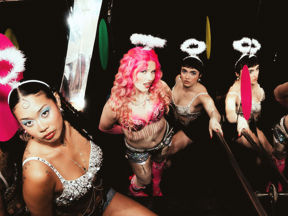 Meg Smith and performers at Night Club 101 in New York City, three performers in sequined outfits and angel halo headbands posed in a mirrored room with colorful circle props reflected throughout