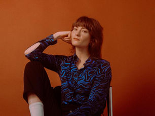 Artist Rowena Wise sitting on a chair looking directly to the camera 