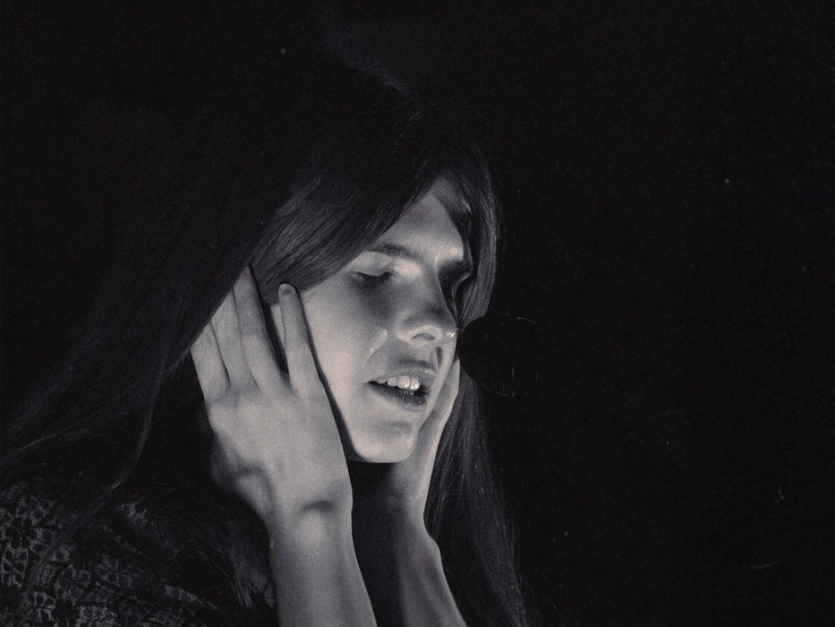 Catie Turner performing at Trans-Pecos in New York City, vocalist with hands raised to her face singing with eyes closed in a black and white photo against a dark background