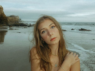 Cinematic Indie Folk singer, Jazmine White, on a beach looking into the camera