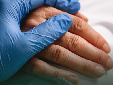 Nurse touching the hands of a patient recovering from an operation. Both of them are in patients home.