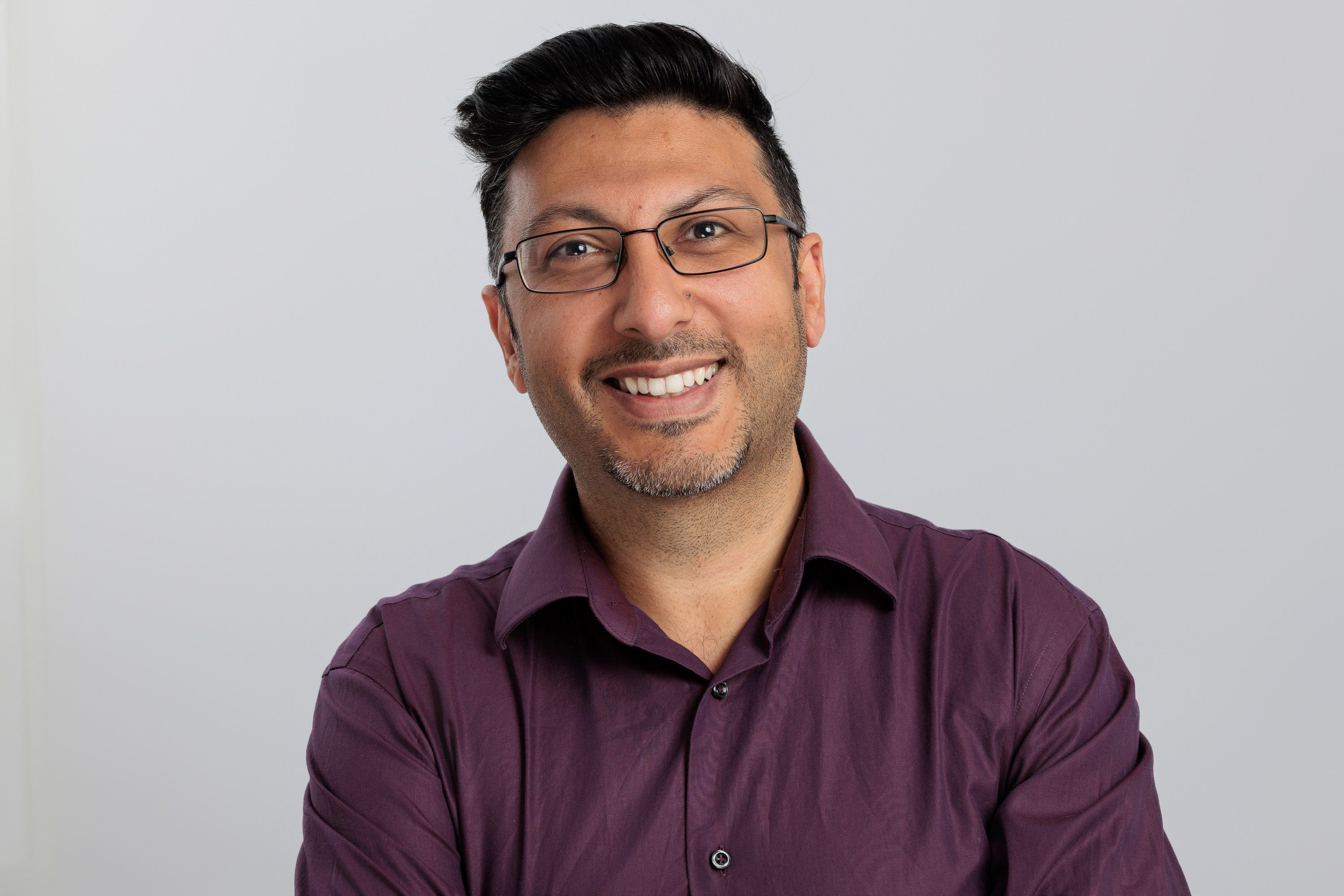 a smiling man getting his headshot taken in a studio