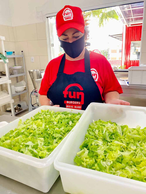 Funcionária da FunBurgers preparando alface.