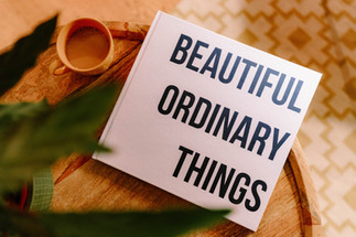 A book, Beautiful Ordinary Things and a coffee and a plant on a table