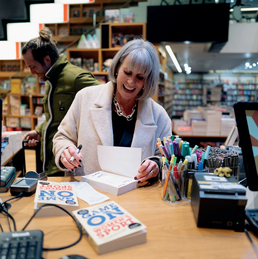 Sue Anstiss smiles whilst signing copies of her book in a book shop