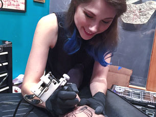 Tattoo artist Secret Kunkle tattooing a person's arm
