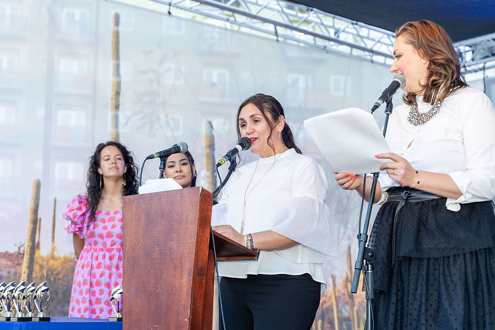 woman speaking at mic and podium surroiunded by coworkers