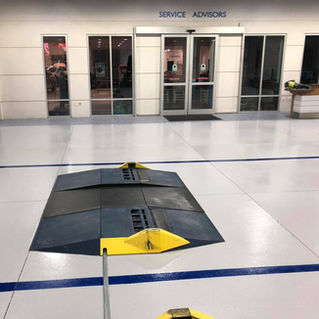 A professional auto shop with Tru-Solid Blend Pearl White epoxy flooring, offering a clean, bright, and durable surface. The high gloss finish provides a sleek look, enhancing the workspace's overall efficiency and aesthetic.