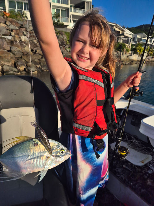 Child holding a trevally aboard a Whitsundays fishing charter boat