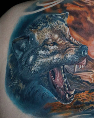 Colour back piece tattoo of a wolf and bear with a landscape background. Made in Llangefni, Isle of Anglesey, North Wales by Shelley Williams.
