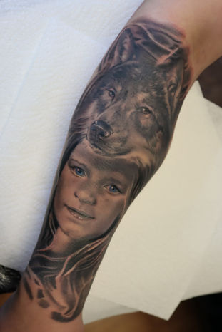 A black and grey portrait tattoo of the clients child with a wolf. Made in Llangefni, Isle of Anglesey, North Wales by Shelley Williams.