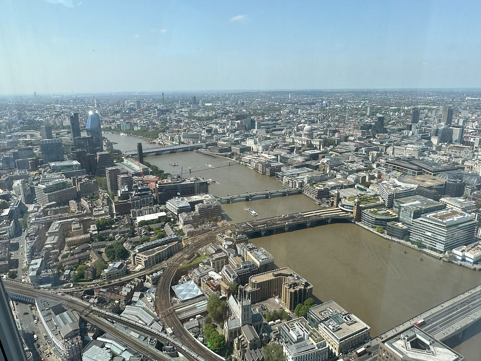 Aerial view of London, featuring the River Thames, bridges, and buildings under a clear blue sky. Urban landscape with a bustling vibe.