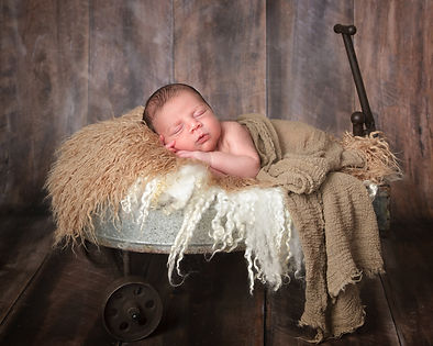newborn baby boy in a vinage metal wagon on his side