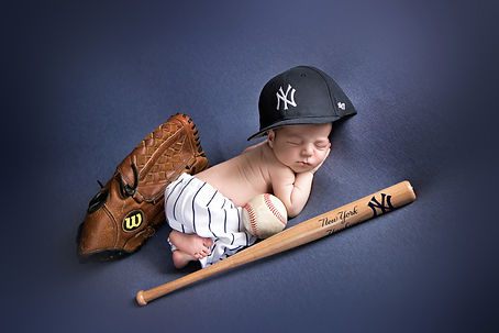 newborn baby boy wearing a yankee hat and pin stripe pants with a NY yankee bat , a baseball and glove