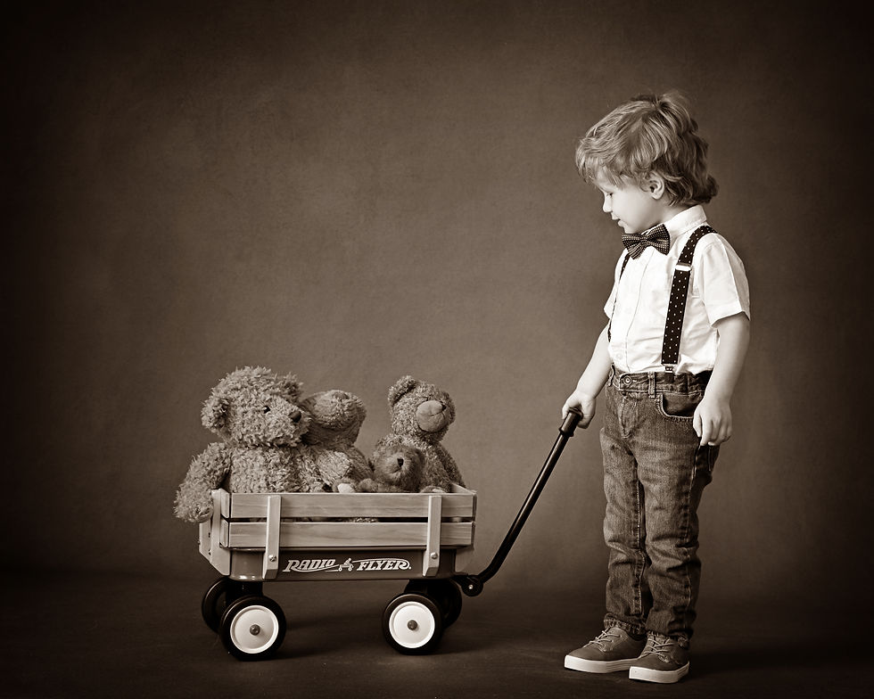 Child in bow tie and suspenders pulls a wooden wagon with teddy bears. Sepia tone gives a nostalgic, vintage feel. Text: Radio Flyer.