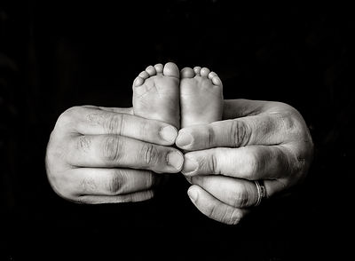black and white of dad's hands holding the baby's feet