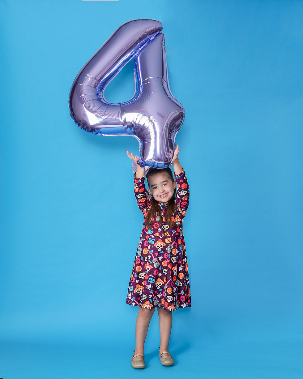 Girl on blue background holding a 4 ballon over her head