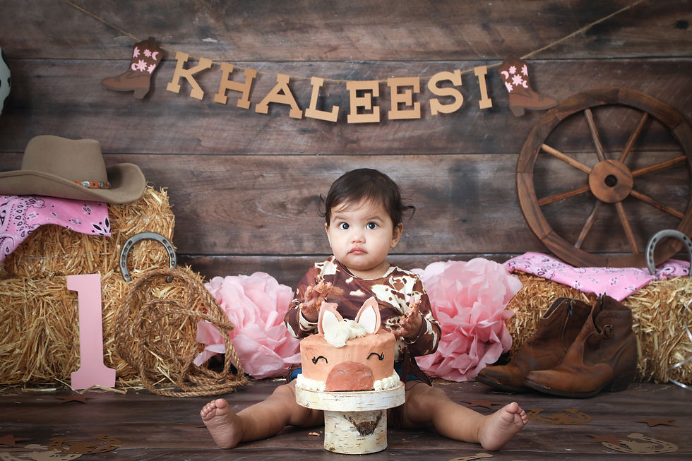 Girl with a horse cake . Set has cowboy hat, hay bales, wagon wheel, boots , horseshoe .
