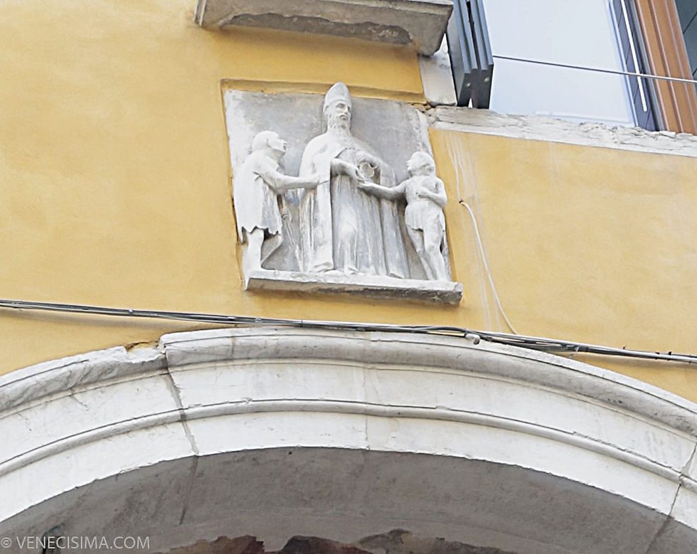 Sobre el arco que precede a la entrada, representación de San Zuane dando limosna a los pobres