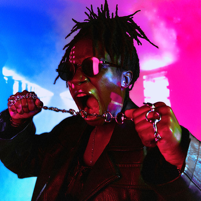 Photo of Nik Nak wearing sunglasses, holding a chain across her open mouth
