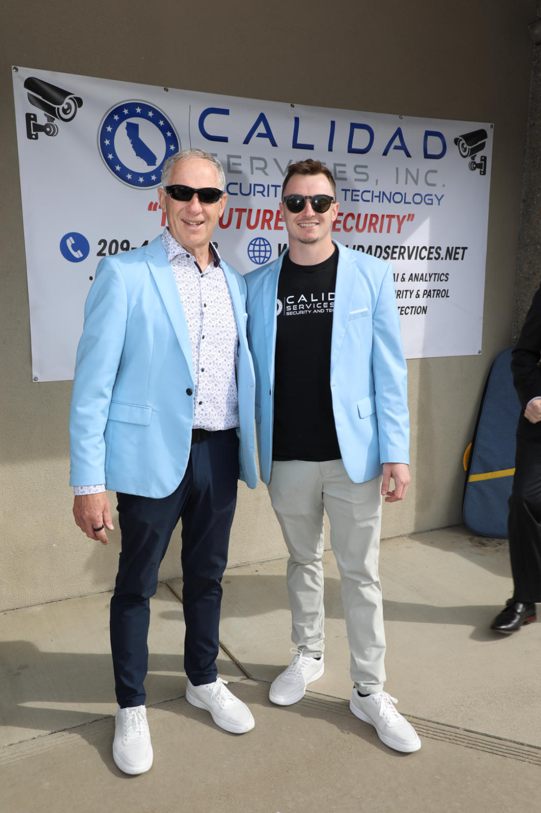 Calidad Services founders Dennis Smallie and Blake Smallie in front of the Calidad banner