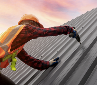 Hartley Roofing contractor fastening a metal roof in Kansas at sunset, highlighting safety practices, precision installation, and dedication to quality workmanship.