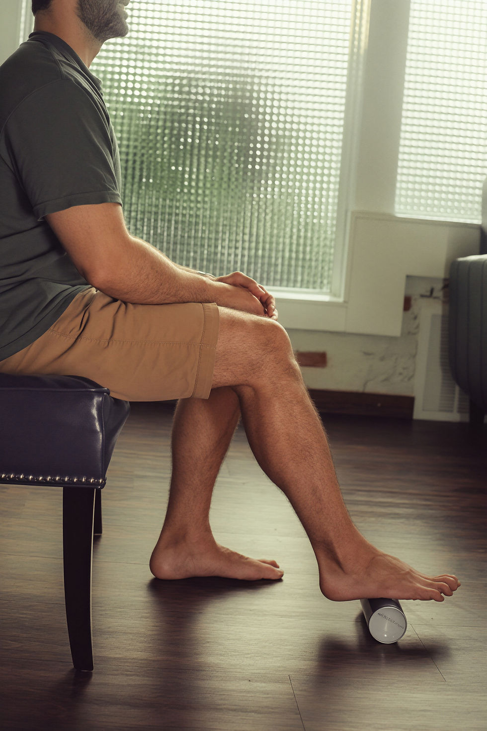 Rolling the bottom of the foot over a frozen water bottle for heel pain relief