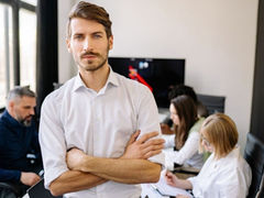 Man standing with crossed arms in a meeting