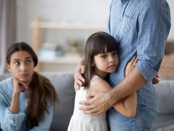 Girl hugging dad with mom in the background looking disapprovingly