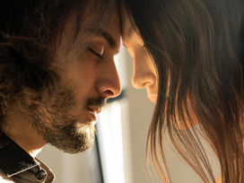 A couple sharing a moment of connection, eyes closed, head to head with each other.