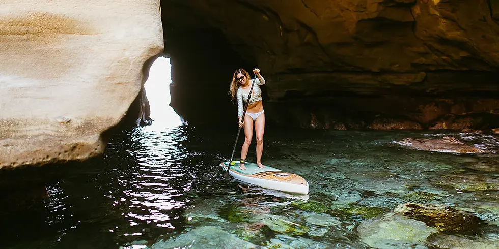 A woman paddle boarding in a cave in San Diego, La Jolla