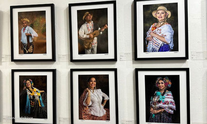 Vista amplia de la galería con cuadros de retratos folklóricos colgados en paredes blancas.