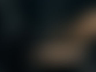 A man in a dark coat examines a round mirror in a dim room, light streaming through a small window onto a sundial. The mood is mysterious.