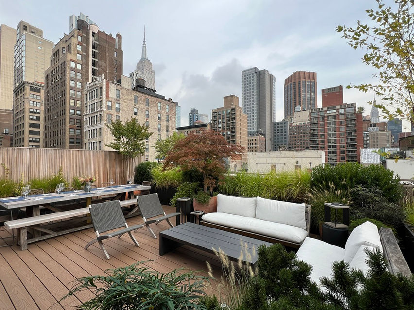 Contemporary rooftop dining area in Gramercy penthouse with modern outdoor furniture, lush plantings, and NYC skyline views