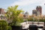 A sectional sofa and lounge chairs on a small rooftop garden in Manhattan NYC.
